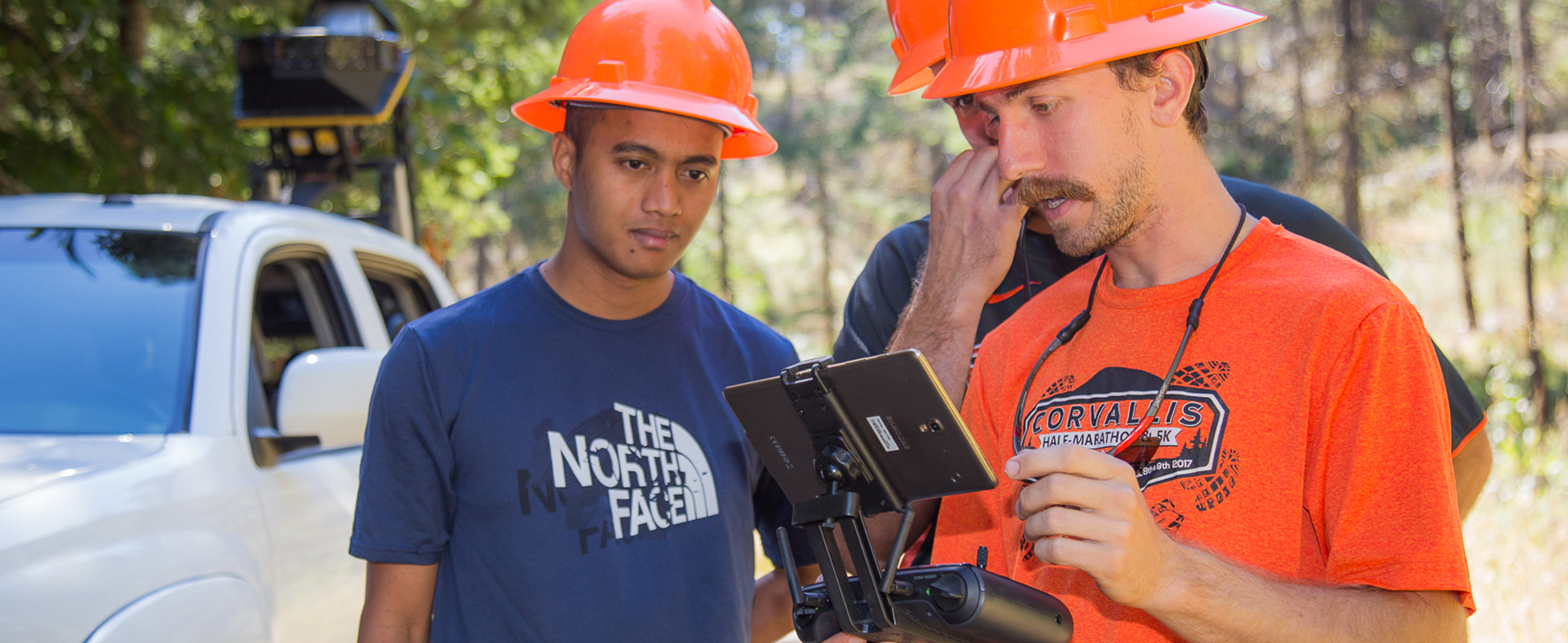 A group of people use technology in the forest.