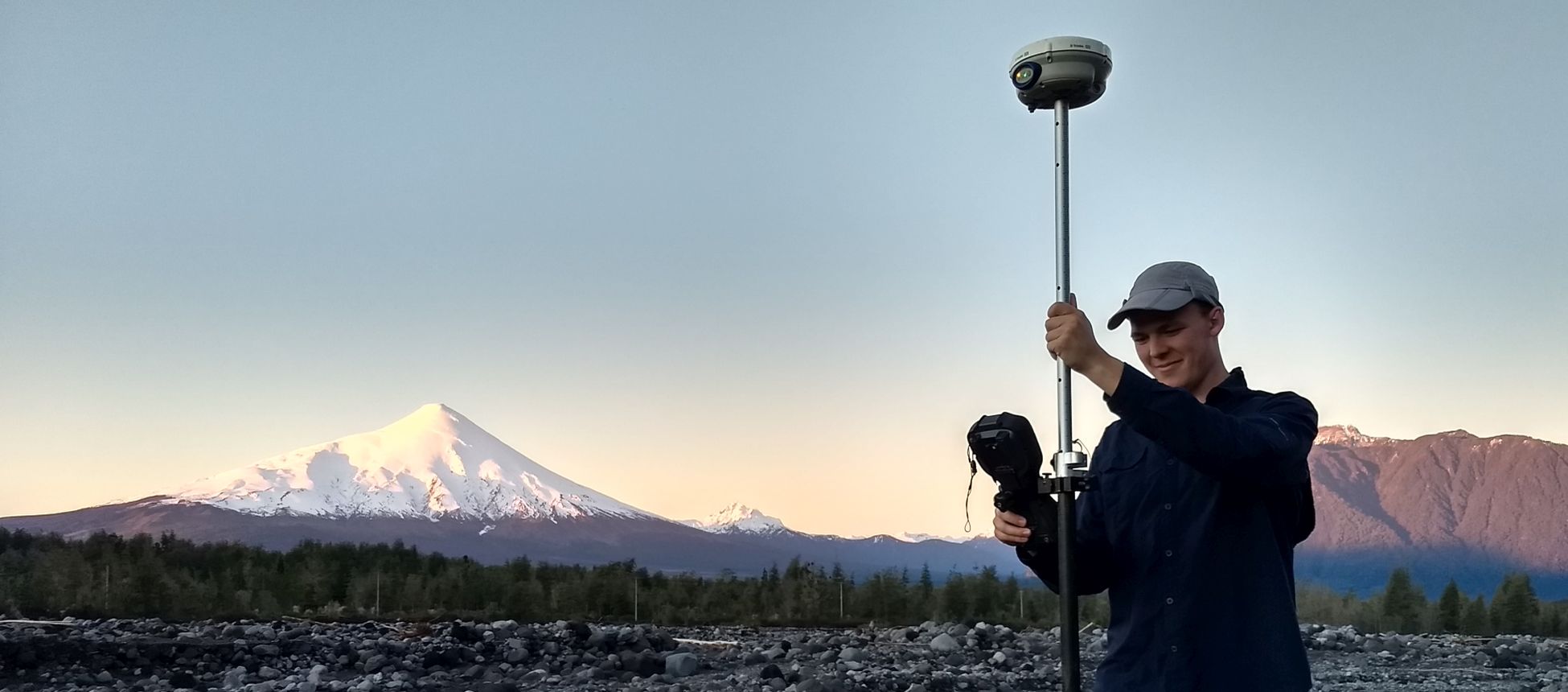 Student with equipment in front of a snow capped mountain